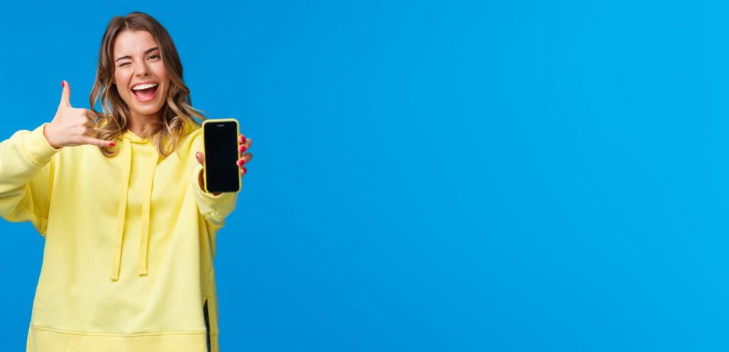 girl say hit me up as trying get hot guy number, holding smartphone, showing mobile phone display, wink and make phone gesture, ask give her call, standing blue background